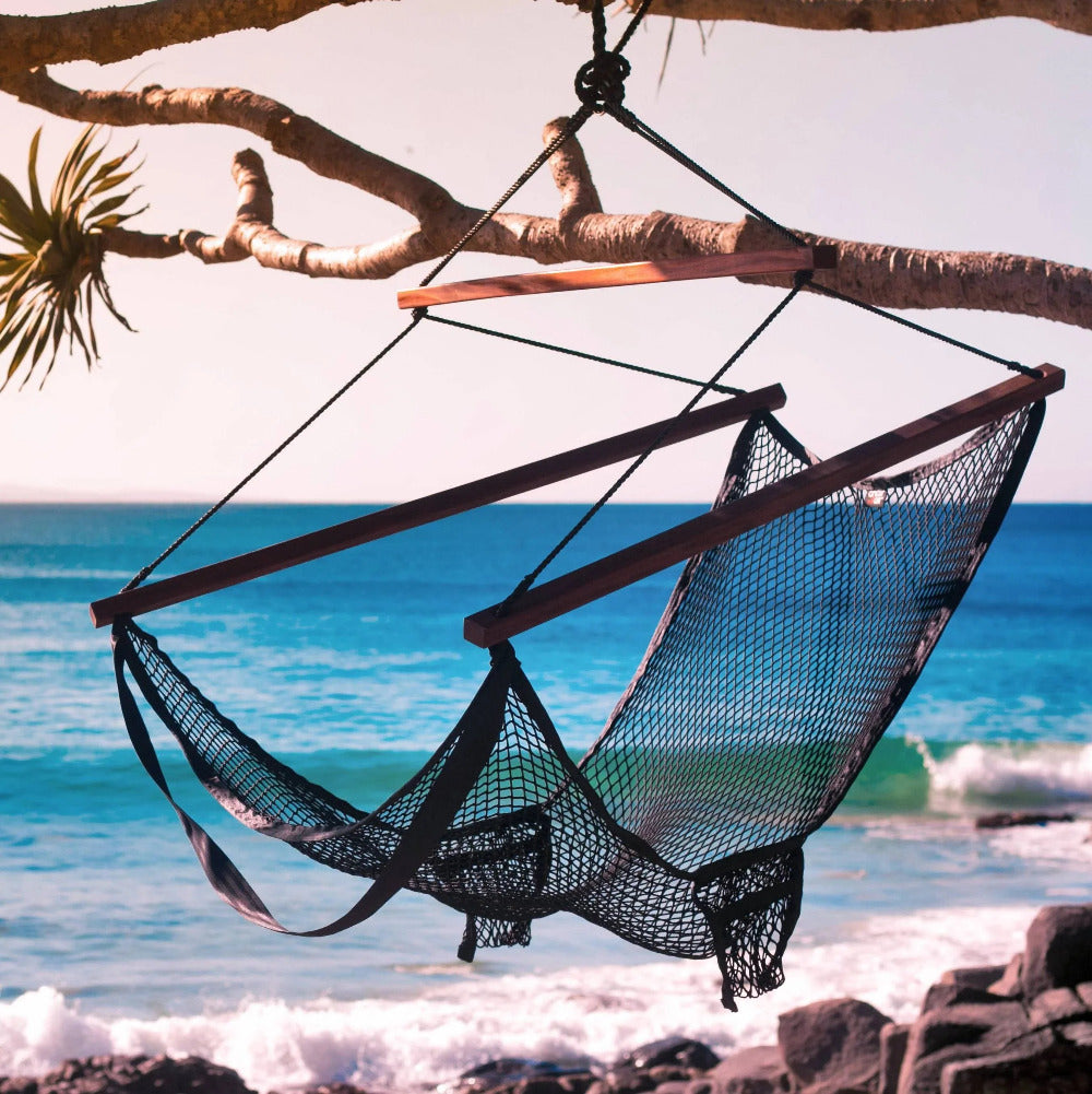 Hammock Chair hanging from a tree branch over a beach with ocean view